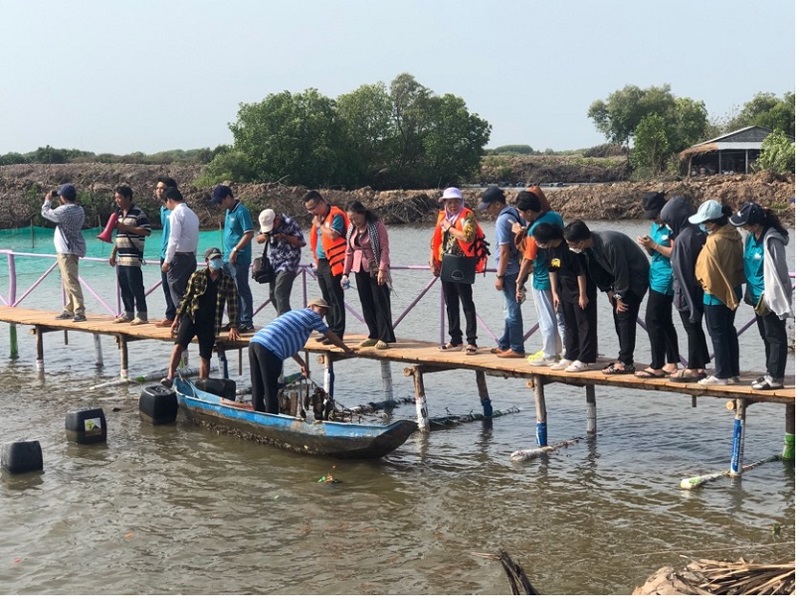 A group of people standing on a bridge over waterDescription automatically generated